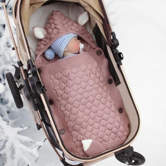 un bébé dans un nid d'ange rose en frome de renard a l'intérieur d'une poussette 